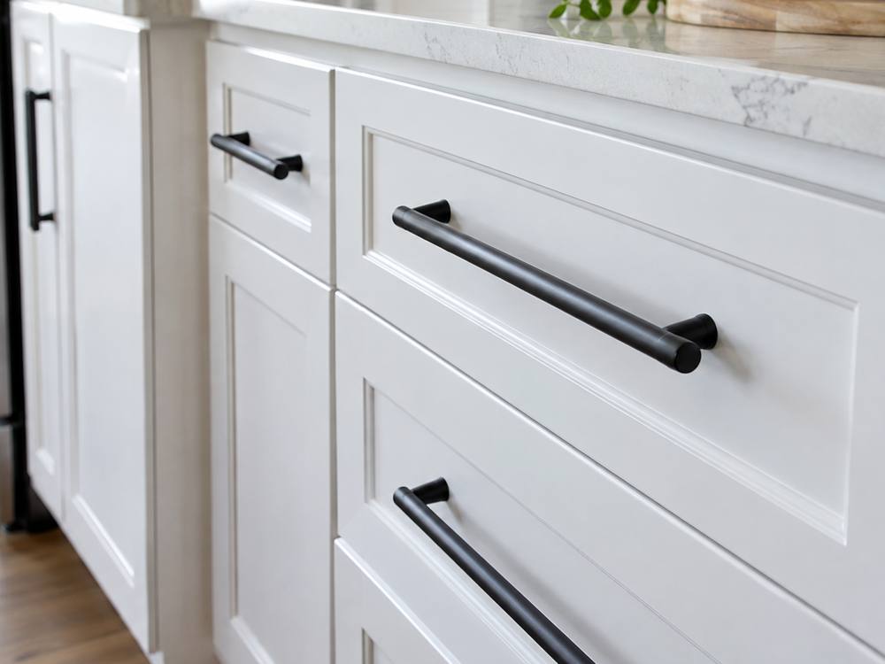 Matte black bar pulls on white shaker drawers with a marble counter